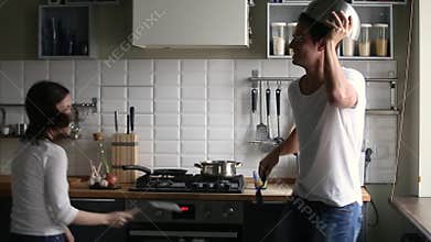 Funny couple pretending fight or kitchen war holding utensils