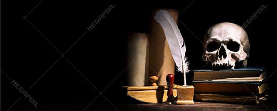 Drama or theater and literature concept. Old inkstand with feather near scrolls with skull on books against black background.