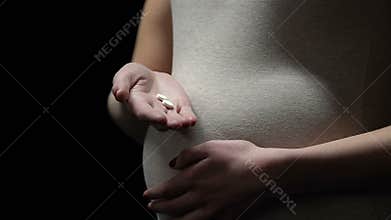 Pregnant woman holding pills, risk of birth defect after medicine, abortion drug