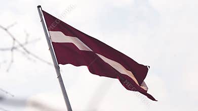 Latvian flag fluttering in the wind high up in the sky during a Golden Hour sunset - Riga capital, Latvia - Dambis AB