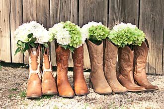 Row of cowboy boots and bouquets at a country theme wedding