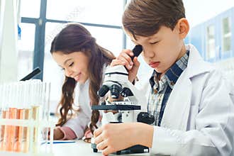 Little kids learning chemistry in school laboratory microscope experiment