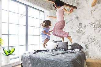 Mother and daughter jumping on the bed