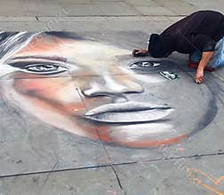 A street artist at work kneeling on the ground in London`s Trafalgar Square