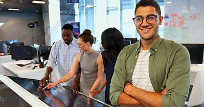 Male executive sanding with arms crossed while colleagues working in office 4k