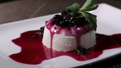 Footage of a panna cotta cake on a white plate, the shot is moving from the left to the right