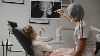 Office dentist orthodontist dentist shows x-ray images of the teeth and holds advice and bracito.