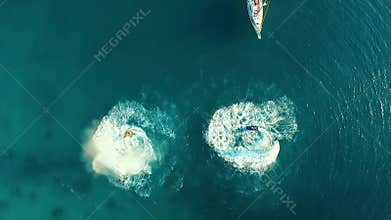 Aerial: Two men flyboarding near the boat.