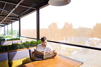 Prosperous man reading newspaper articles and resting.