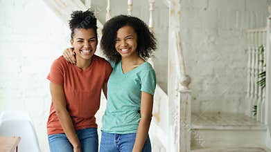 Portrait of two beautiful african american girls laughing and looking into camera at home
