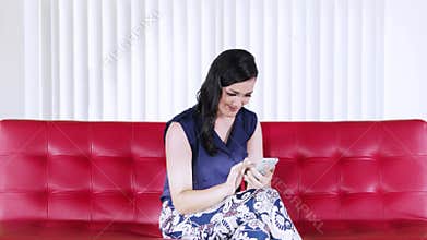 Casual woman uses cellphone on red couch