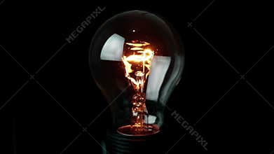 Turn on and turn off, retro vintage light bulb with tungsten technology built-in on black background, old style atmosphere