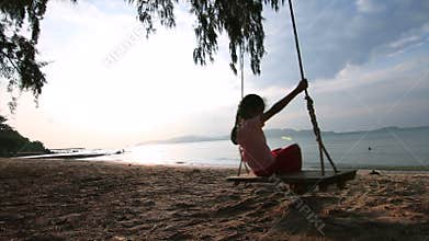 4K Slow motion Asian little girl playing swing on the beach with evening ambient light