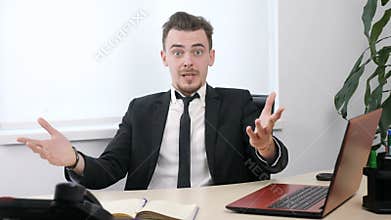 Young businessman in suit is sitting in office and is surprised 60 fps