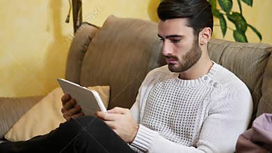 Handsome young man at home, using tablet PC
