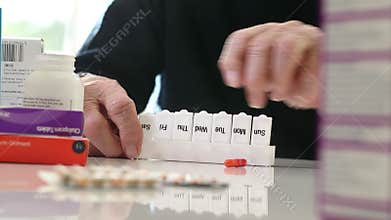Close Up Of Senior Man Organizing Medication Into Pill Dispenser