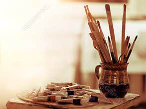 Paint brushes art pot. Easel with oil and watercolor paints.