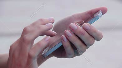 Close-up of woman's hands with nice manicure texting, messaging on smart phone