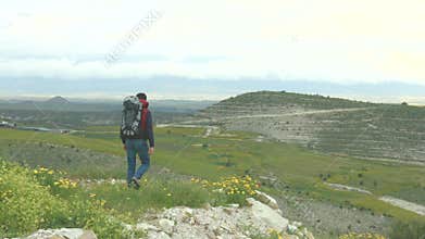 Young man backpacking, enjoying beautiful panorama of green mountain landscape