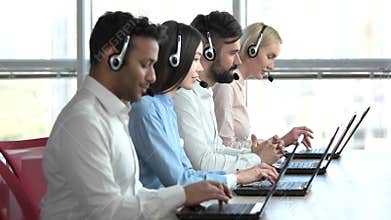 Line of call centre employees working on a laptop computers.