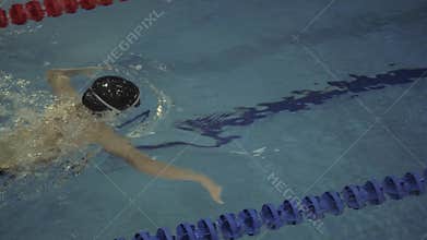 Woman swimmer in goggles floating breaststroke in water swimming poo