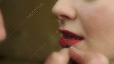Makeup artist painting lips with red lipstick. Famous actress before talk-show