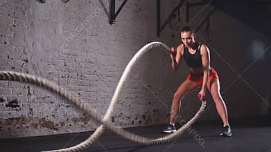 Battling ropes girl at gym workout exercise fitted body. Slow motion