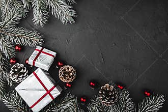 Upper, above, top view of pine, evergreen, and Christmas red glass toys, presents on stone background.
