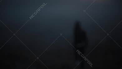 Portrait of Caucasian girl walking away into fog. Beautiful mysterious female looking back at camera and disappearing.