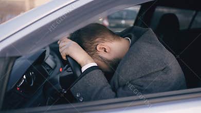 Young bearded business man sitting in car very upset and stressed after hard failure and moving in traffic jam