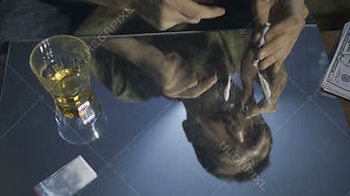 Reflection of male portrait snorting coke line