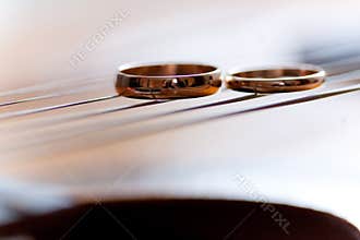 Two wedding rings are on guitar stripes