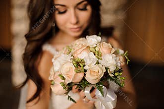 Cute bride holding wedding bouquet of white and peach roses