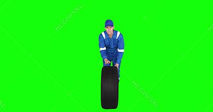Auto mechanic pushing tire in studio