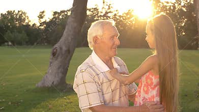 Grandpa and little girl talking outdoors.