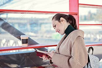 Woman reading a book near the shelves with free books, social library on the street