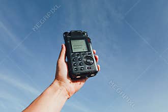 Portable audio recorder in hand recording ambient sounds of nature