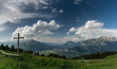 Mountain panorama with a gorgeous view of the Swiss Alps and Valleys and a summit cross