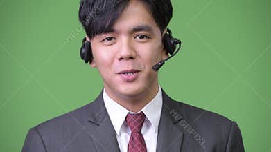 Young handsome Asian businessman working as call center representative