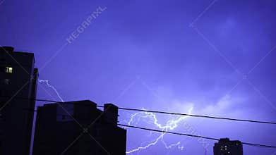 Lightning in the night sky in the city, a bright flash of light in the clouds in the rain, a thunderstorm