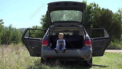 Funny child waiting in car trunk, calculating the remaining time to leave in holiday