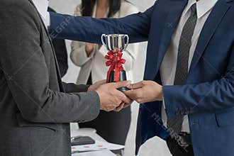 Manager giving employee the trophy award for success in business