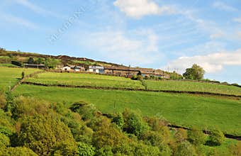 West yorkshire dales scenery with farmhouses on high hills with typical walled fields and moors in the distance