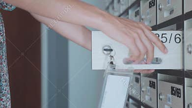 Young woman checking mailbox at condo, indoor