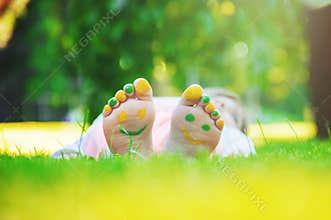 Child lying on green grass. Kid having fun outdoors in spring park.