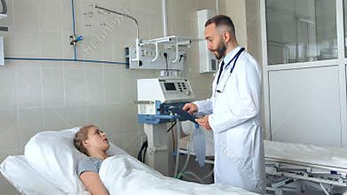 Doctor standing near hospital bed and discussing with young female patient