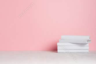 White blank books on white shelf and soft pink wall as modern, elegant home decor.