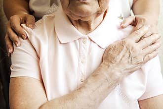 Close up of mature womans & nurse hands. Health care giving, nursing home. Parental love of grandmother. Old age related diseases.