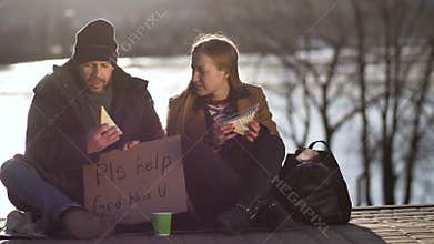 Female sharing sandwich and talking to homeless