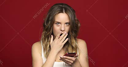Pretty girl looks at mobile phone shocked close up